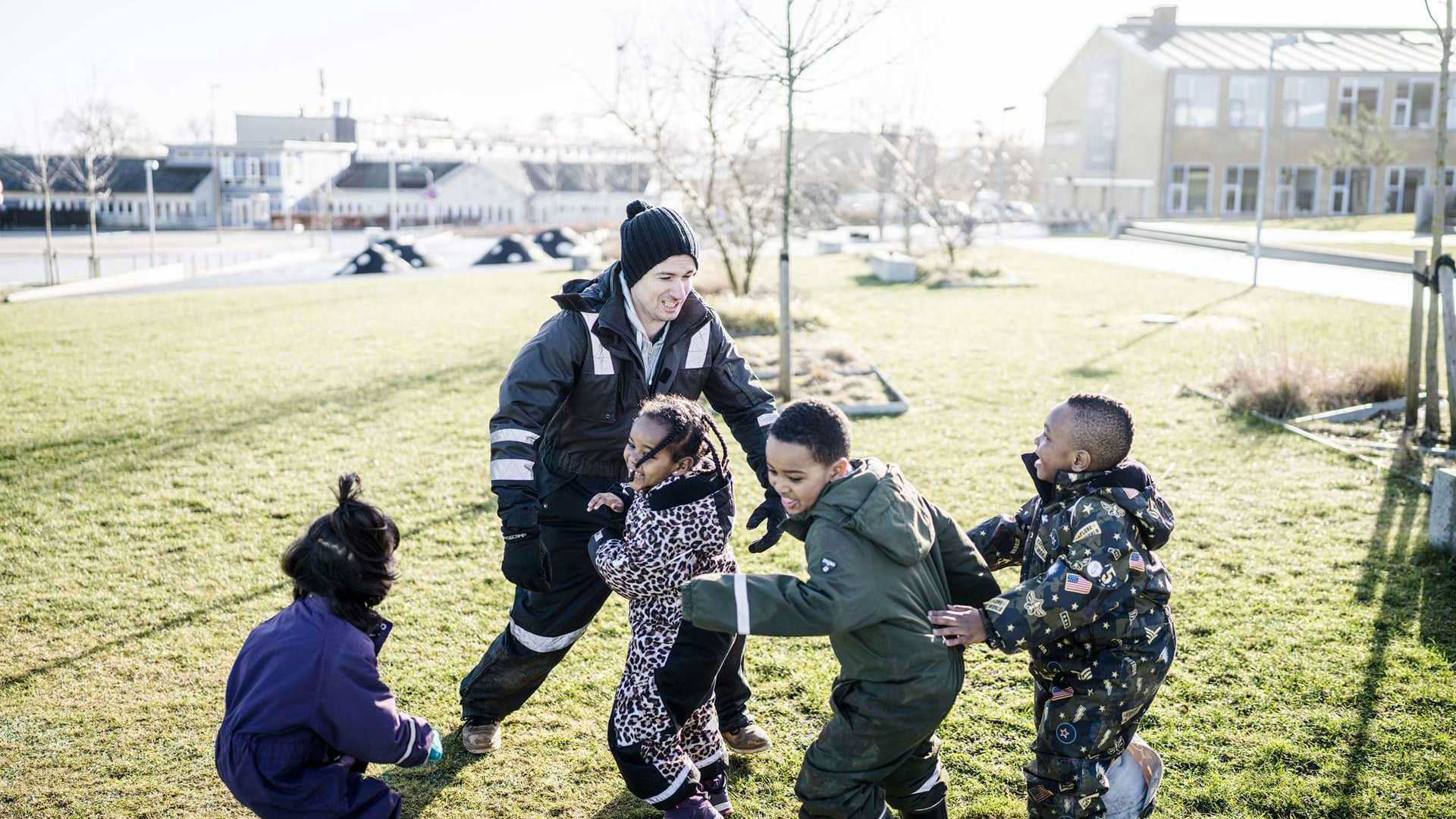 Mandlig pædagog leger med børn udenfor