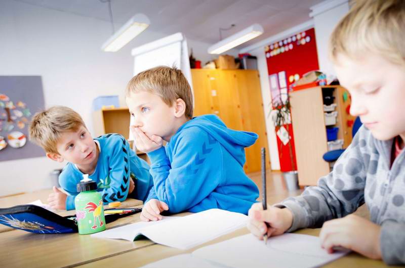 Tre drenge i en klasse med hæfter og penalhus