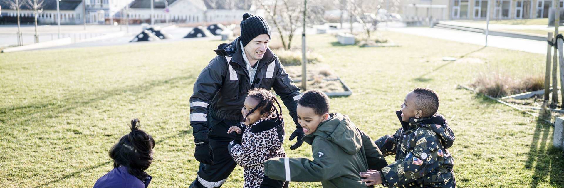 Mandlig pædagog leger med børn udenfor Mandlig pædagog leger med børn udenfor