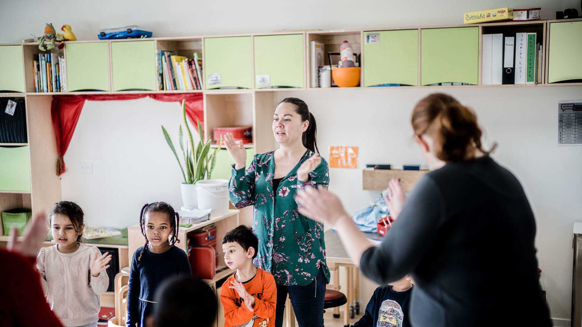 Kvindelige pædagoger leger sangleg med børnehavebørn